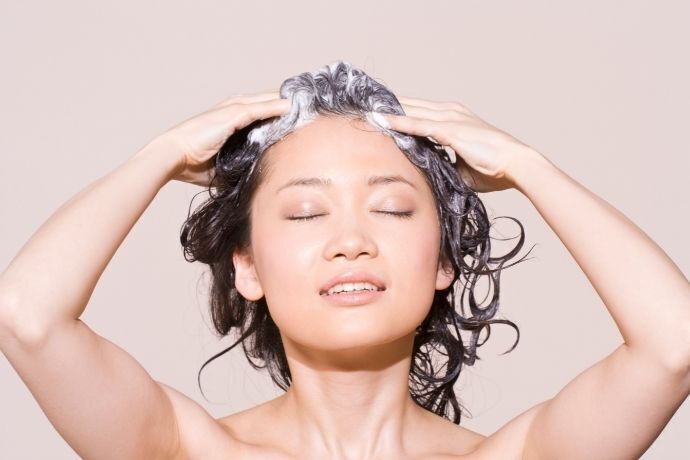 Mulher lavando cabelo com shampoo