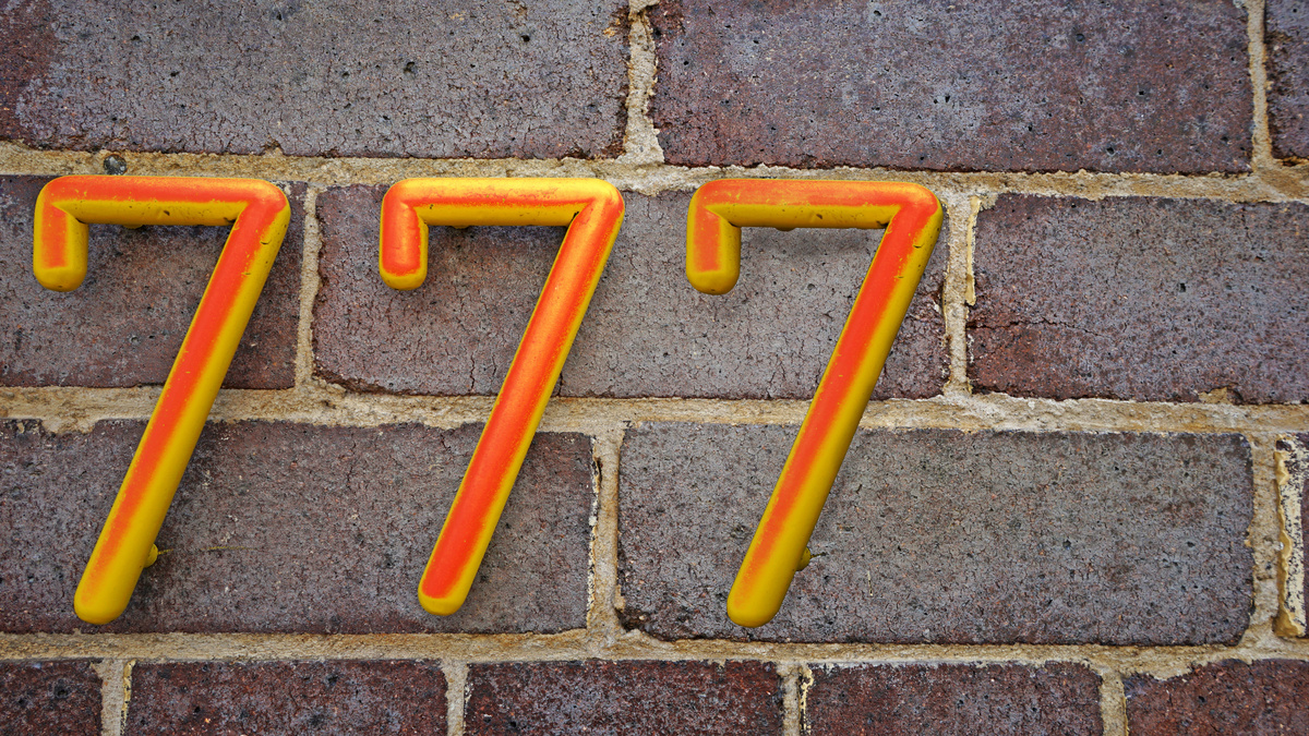 Número 777 em parede de tijolos.