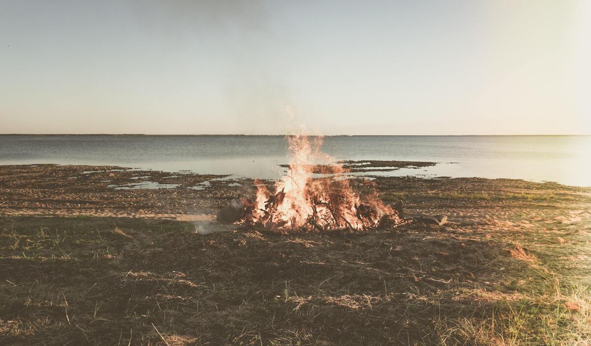 Fogueira queimando durante o dia próximo a uma praia