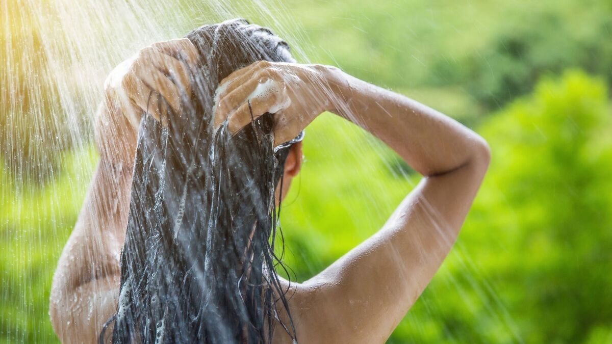 Mulher lavando a cabeça com shampoo.