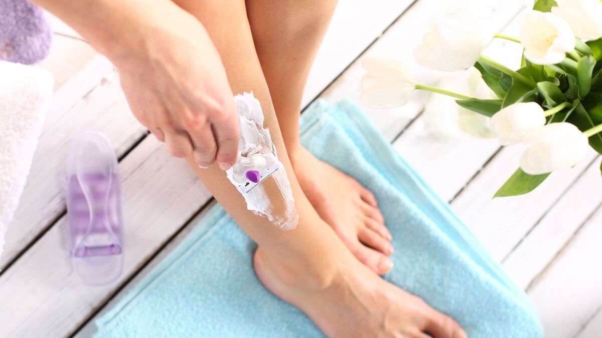 Mulher depilando a perna.