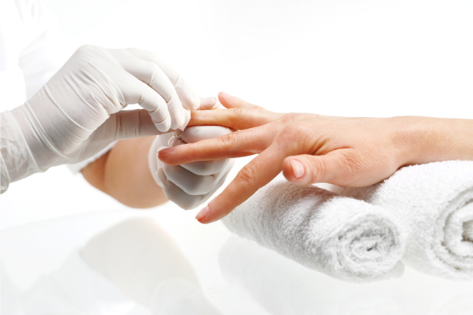 Manicure removendo esmalte de unhas de cliente.