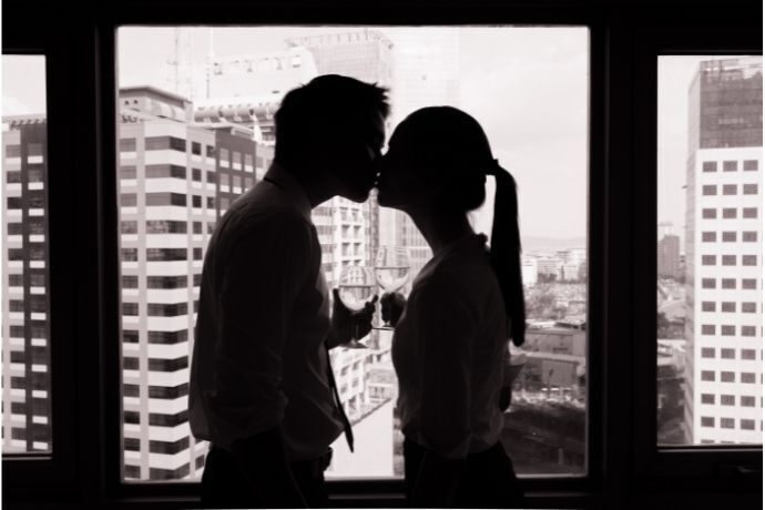 Casal tomando vinho em frente a janela em preto e branco