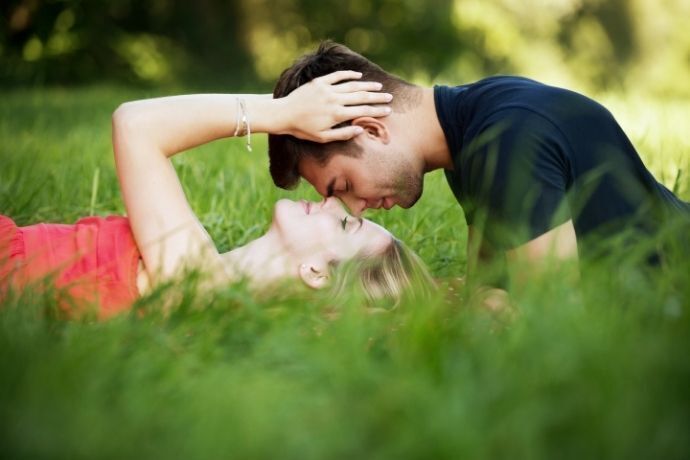 Casal se beijando deitados na grama
