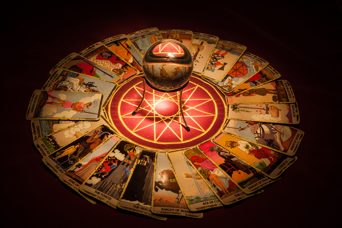 Círculo formado por cartas de Tarot com oráculo no meio, fundo escuro.