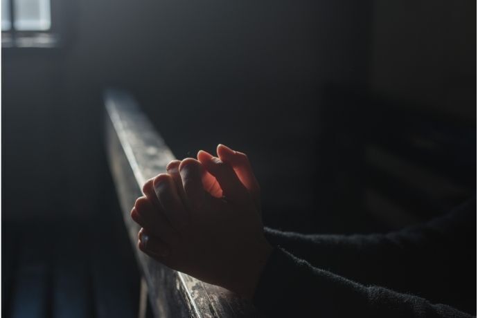 Pessoa rezando em ambiente escuro