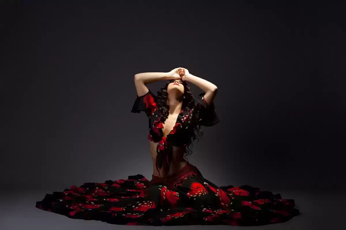 Mulher com vestido preto e vermelho sentada no chão