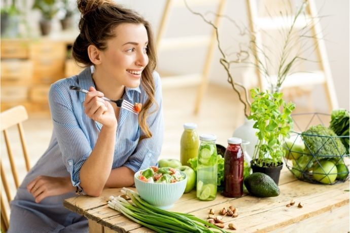 Mulher sentada em mesa com alimentos saudáveis
