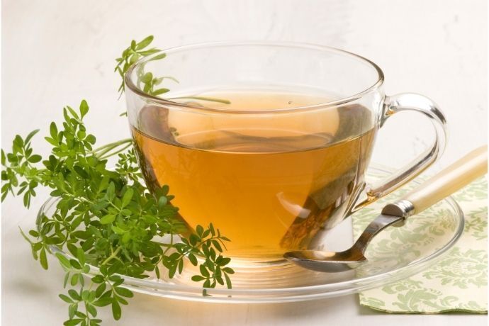 Xícara de chá com folhas de arruda no pires