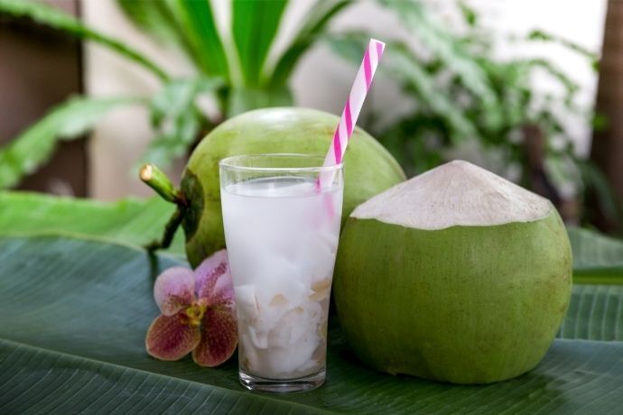 Água de coco em coco ao lado de dois cocos