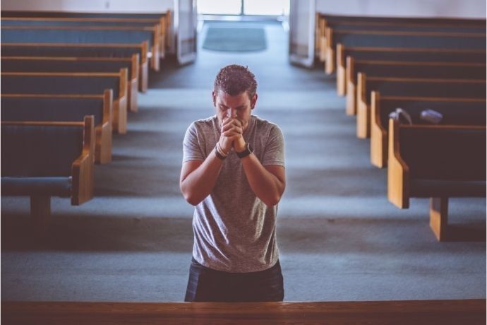 Homem ajoelhado em igreja fazendo oração