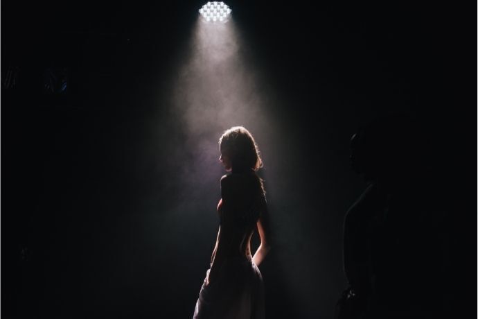 Silhueta de mulher iluminada por luz em palco