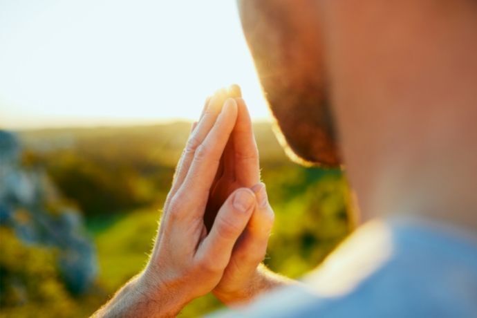 Homem olhando para paisagem e rezando 