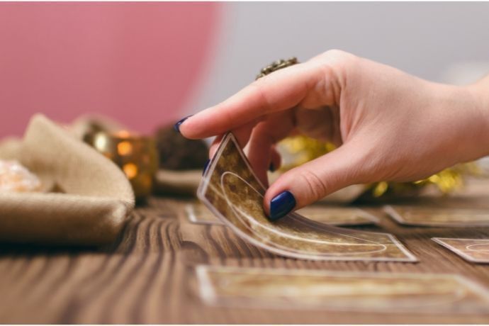 Mãos femininas colocando cartas de baralho cigano na mesa