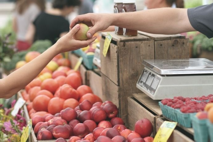 Pessoa comprando maçã em mercado ou feira