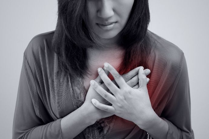 Imagem de mulher em preto e branco com mão no coração destacado de vermelho