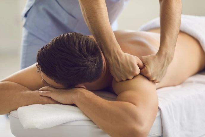 Homem deitado recebendo massagem nos ombros