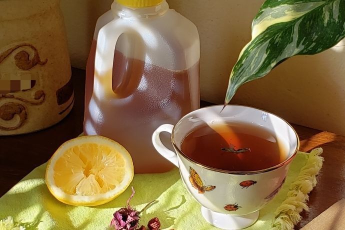 Chá de laranja e mel em xícara, com garrafa de mel no fundo