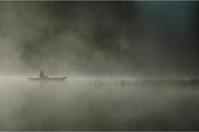 Pessoa navegando em uma canoa em um rio com neblina