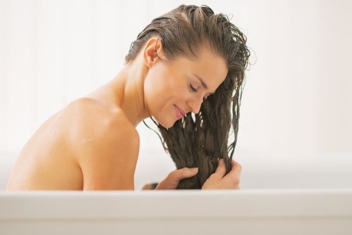 Mulher em banheira lavando cabelo