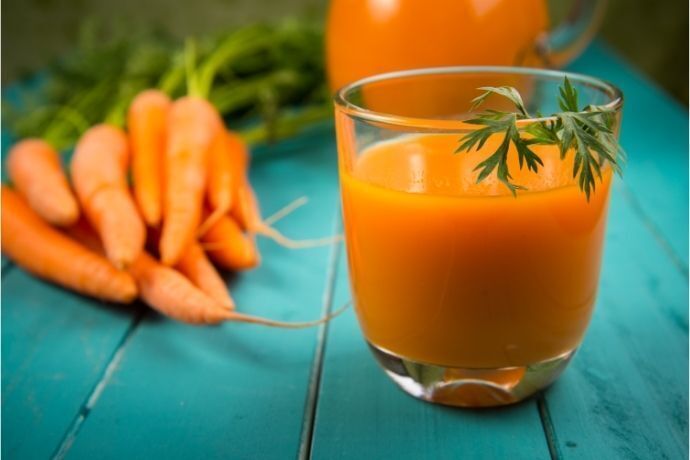 copo com suco de cenoura e cenouras ao fundo