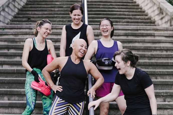 Mulheres rindo em escada com roupas para atividades físicas