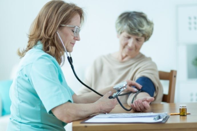 Enfermeira medindo pressão de mulher idosa