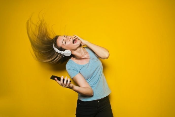 Mulher balançando os cabelos enquanto escuta música em fone de ouvido
