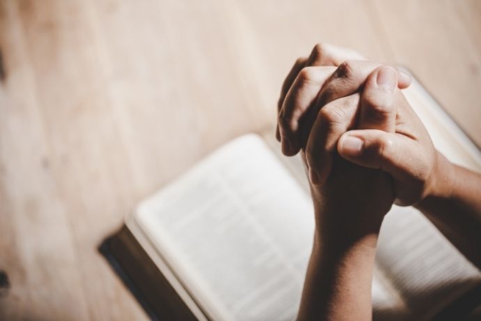 Pessoa rezando com bíblia