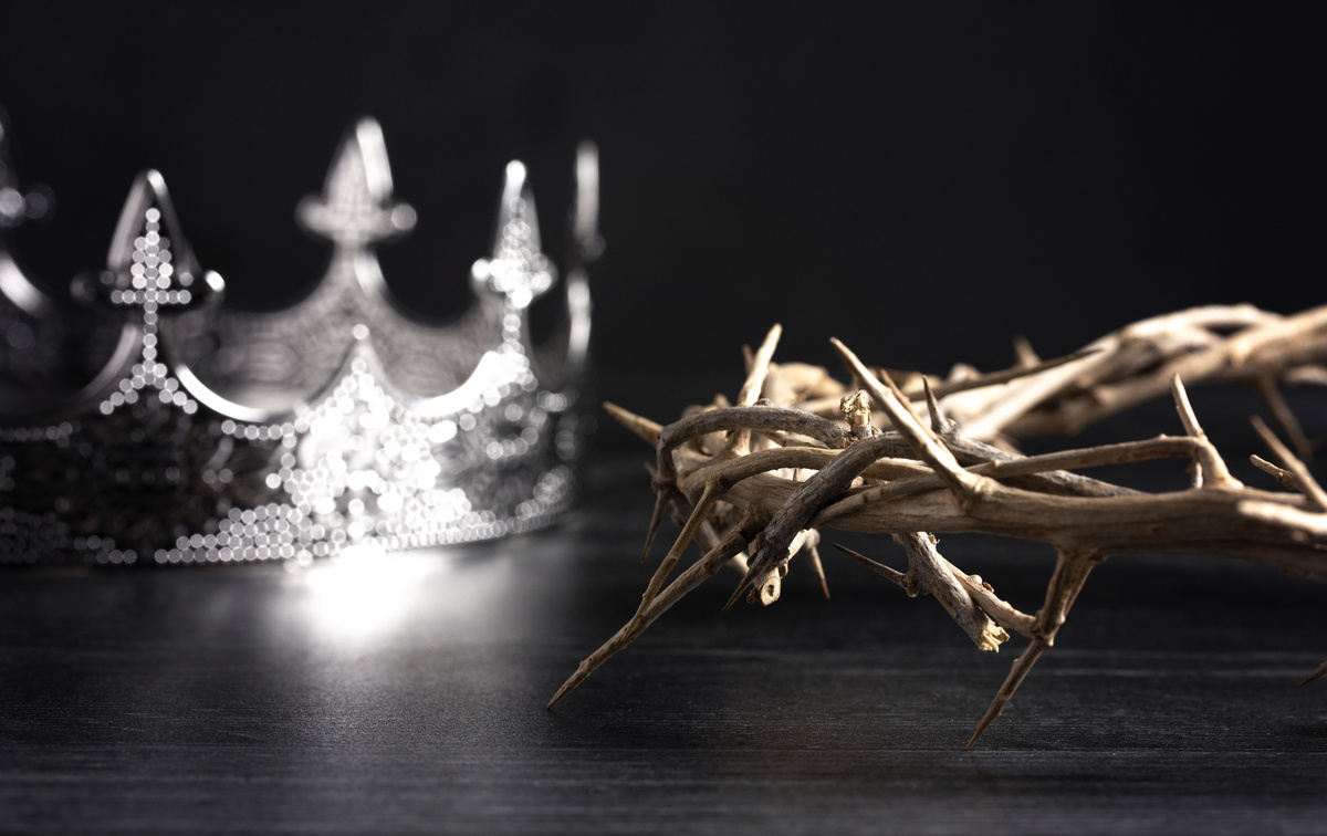 Coroa de prata e coroa de espinhos sobre uma mesa de madeira.