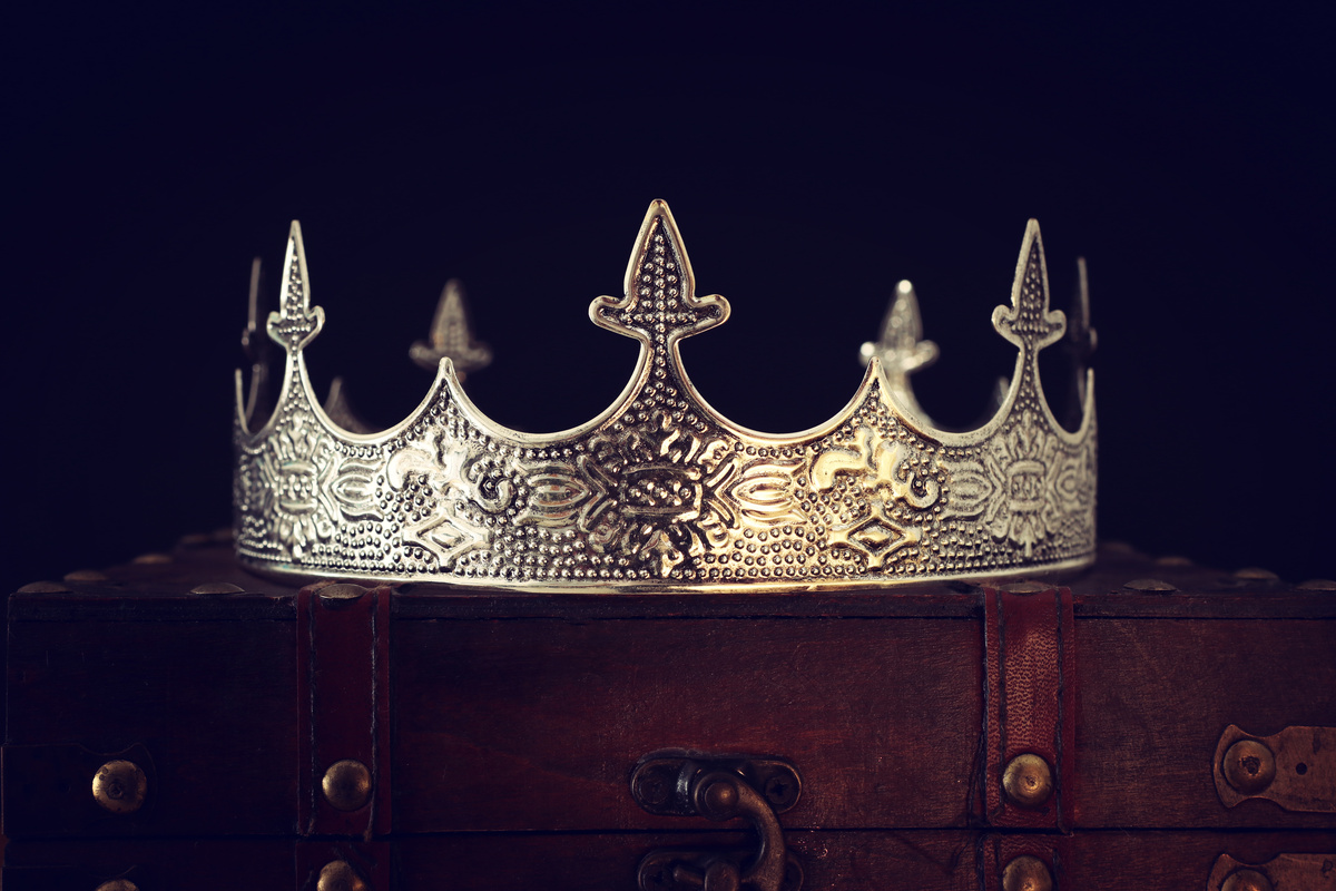 Coroa prata sobre baú de couro.