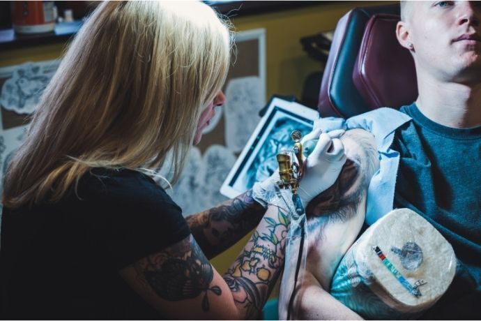Mulher tatuando homem 