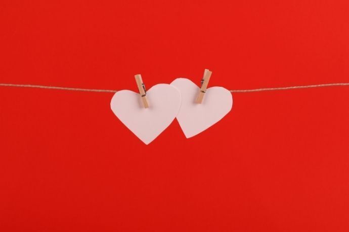 Dois corações de papel pendurados em corda com prendedor de madeira