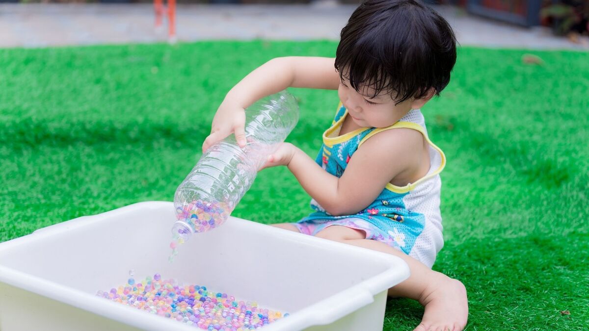 Criança colocando coisas dentro de uma bacia.