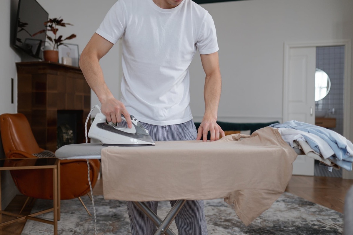 Homem passando camiseta com ferro de passar roupas