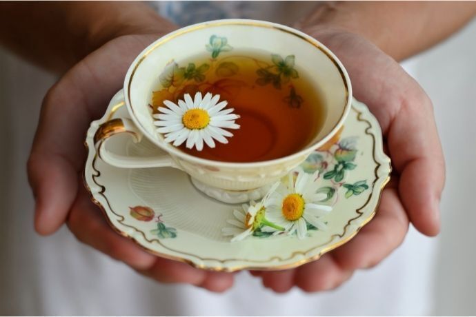 Pessoa segundo xícara com chá e uma flor