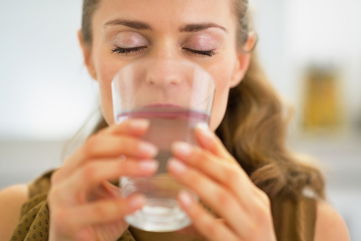 Mulher bebendo copo d'água.