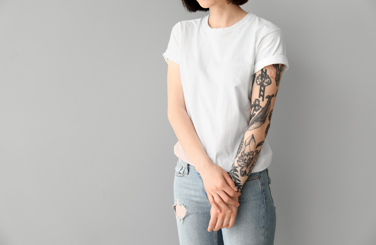 Mulher branca com braço esquerdo tatuado.