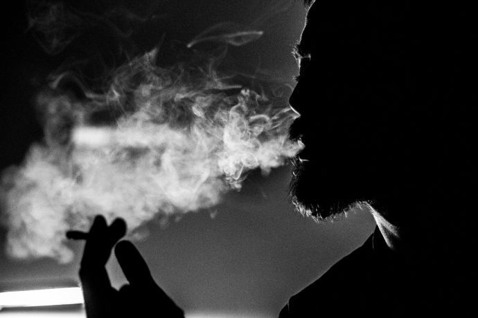 Homem fumando cigarro em preto e branco
