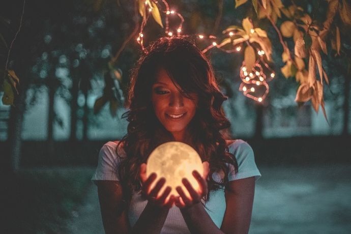Mulher segurando pequena lua brilhante 