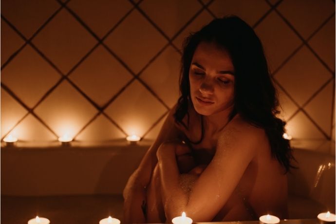 Mulher sentada em banheira com velas