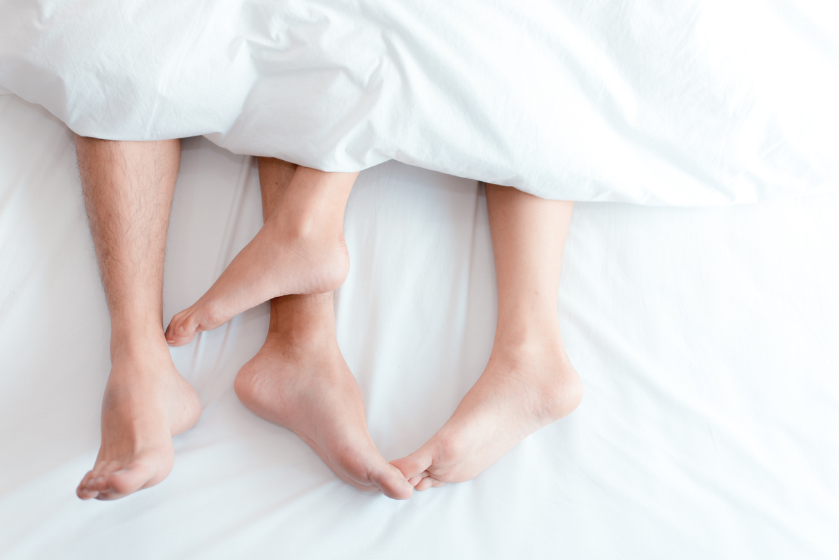 Foco nos pés de casal na cama parcialmente enrolados