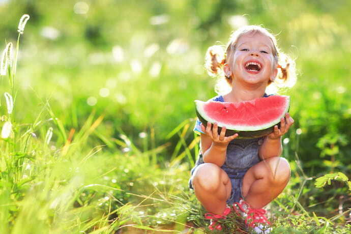 criança feliz comendo melancia