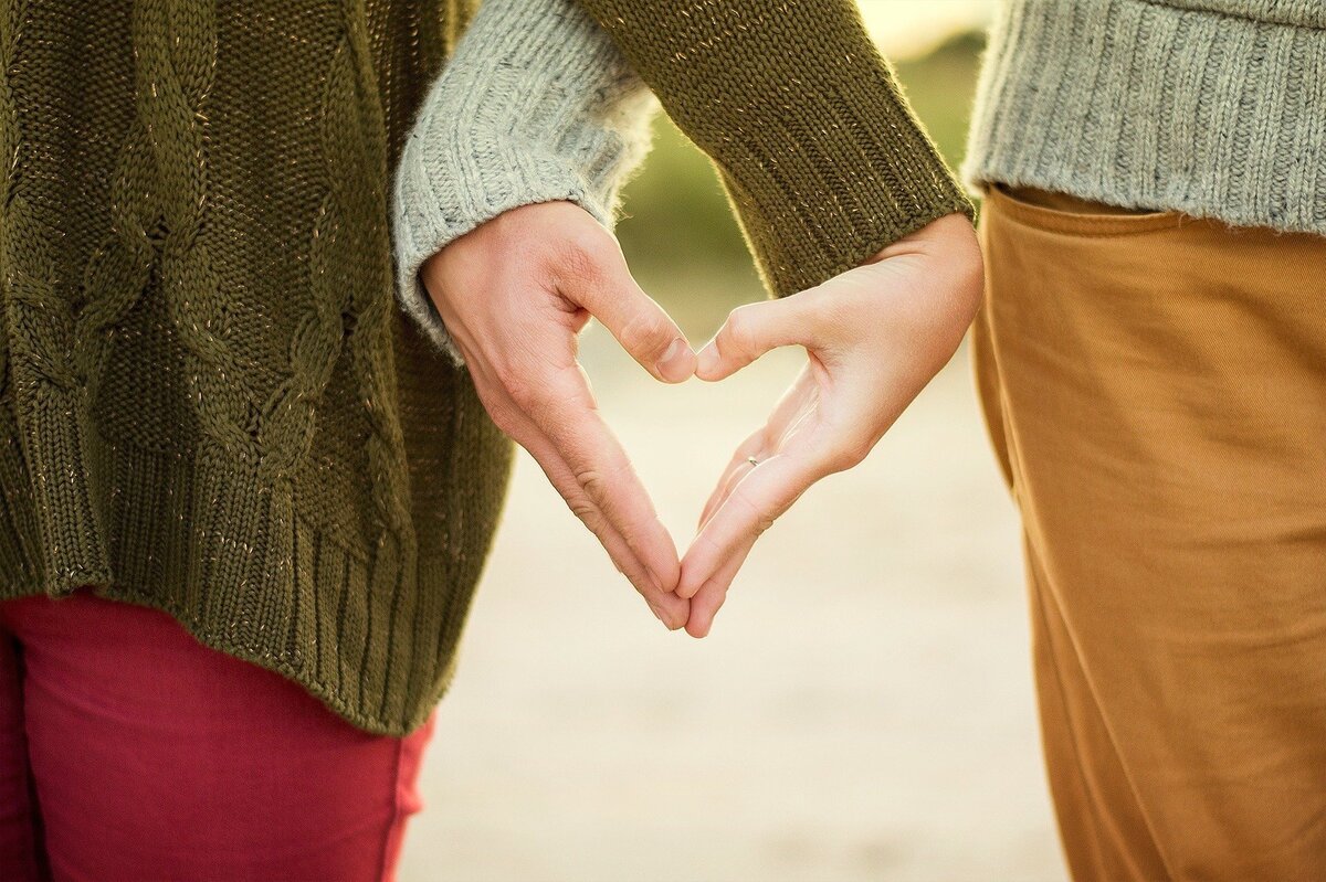 Duas mãos dadas, formando um coração, representando a efetividade da Lei da Atração no amor.