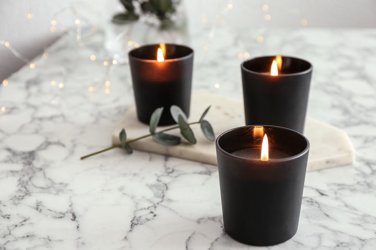 Três velas pretas acesas sobre mesa de mármore.