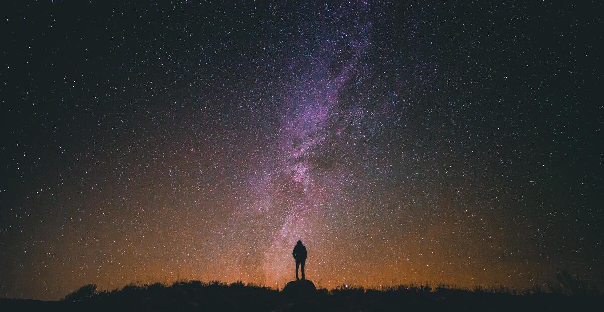 Pessoa diante de céu estrelado. 