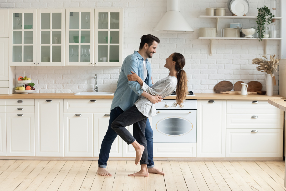 Casal de homem e mulher dançando numa cozinha.