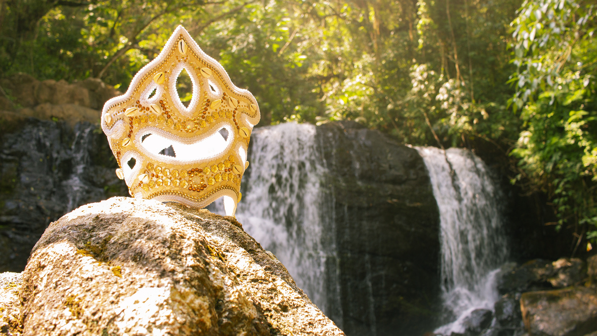 Capacete dourado de Oxum sobre pedras de cachoeiras.