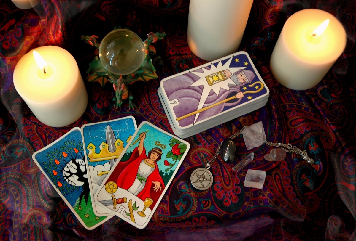 Carta Ás de Espadas combinadas com três outras, em monte separado das demais cartas do Tarot, enquanto em volta de velas.