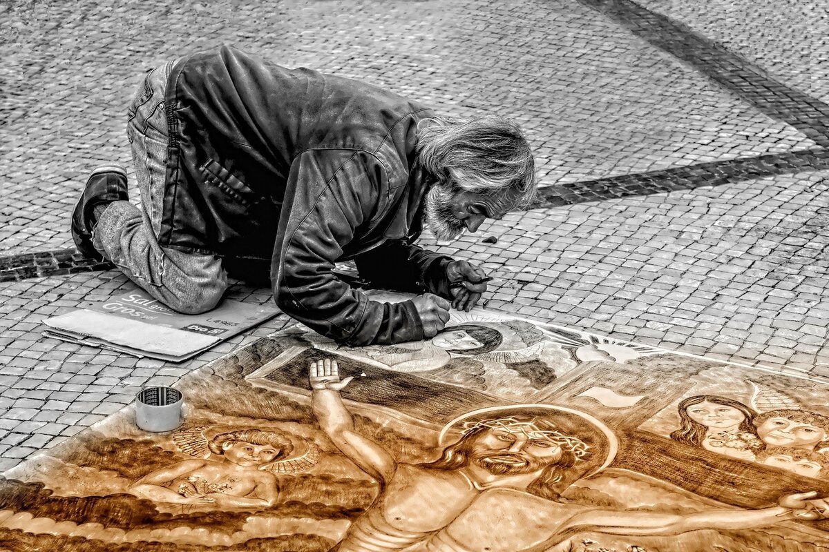 Homem pintando um quadro na rua.